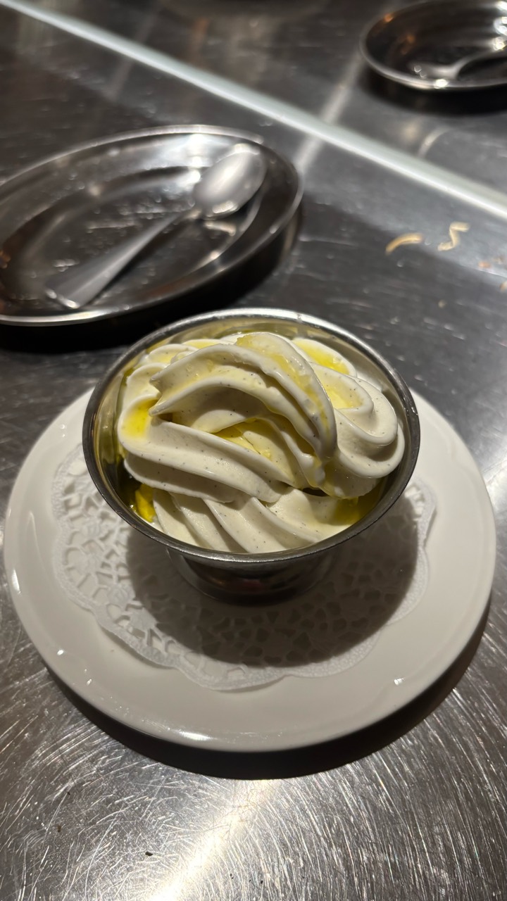 Soft serve with olive oil in a metal bowl on a cafe table